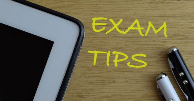 Top view of tablet and pens with “Exam Tips” on wooden background
