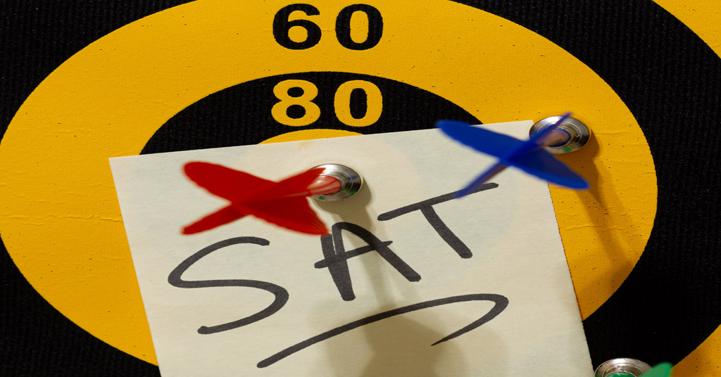 A dart board with multiple arrows and a red arrow hits the bullseye on a note that says SAT.