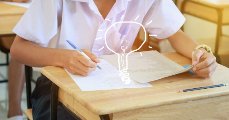 Student writing test on a paper on the desk