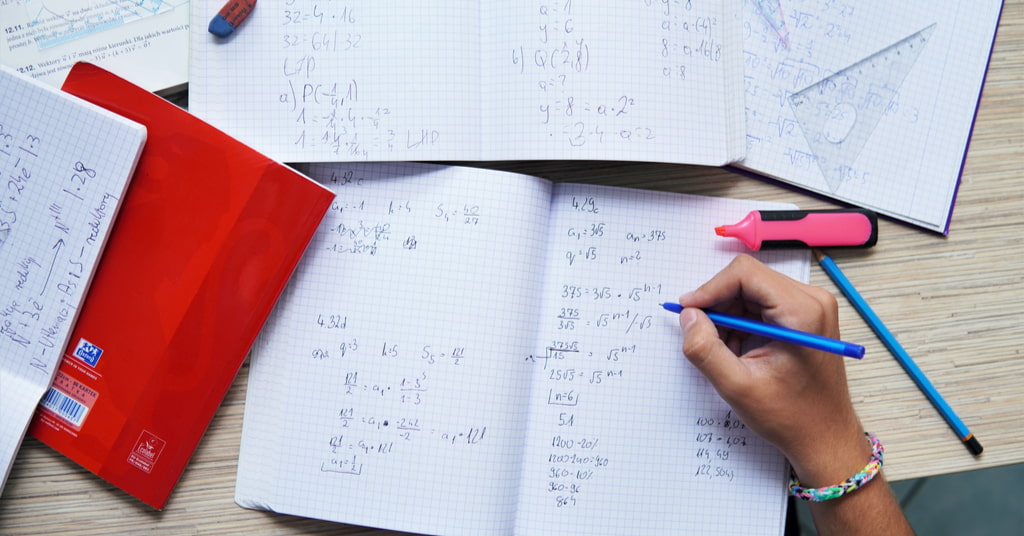 Student solving math problems on white sheets