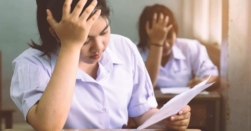 Young girl student reading exam paper