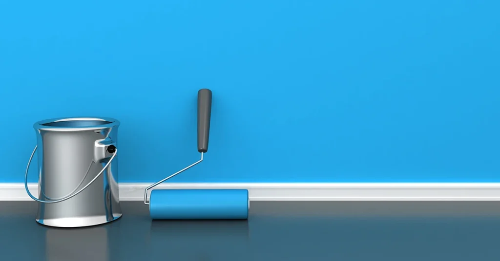 A silver paint can and a paint roller sit in front of a freshly-painted blue wall.
