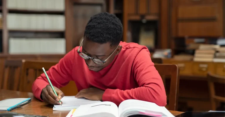 A high school student practicing with SAT study prep book.