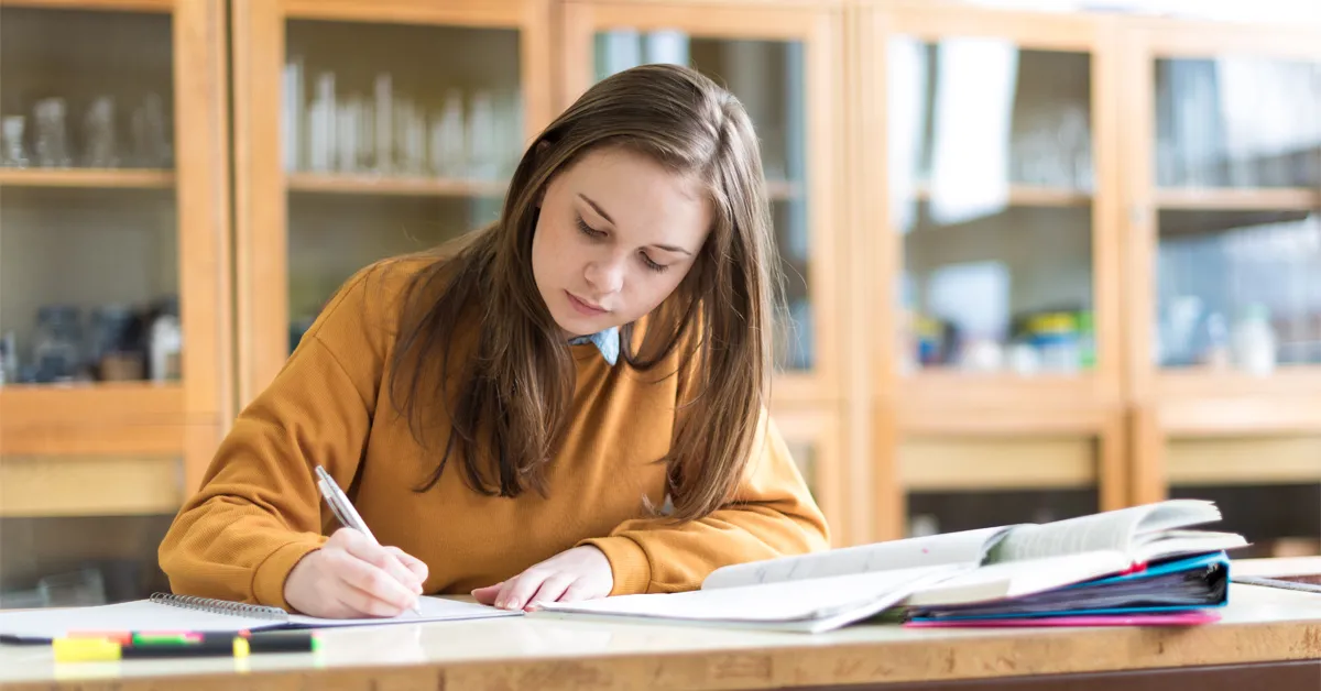A high school girl student practicing questions with UWorld Study guide prep books
