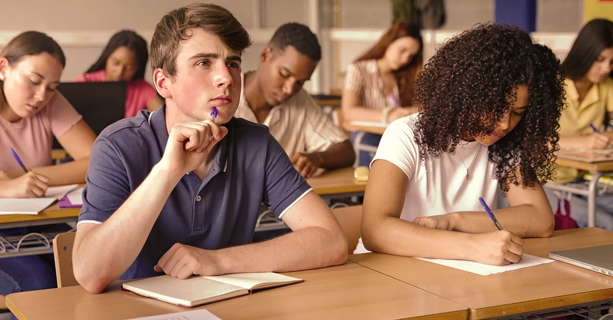 High school students in a classroom setting focused on test prep, with one student appearing deep in thought.