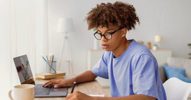 High school student studying with a laptop and notebook at a desk, focused on ACT test prep.