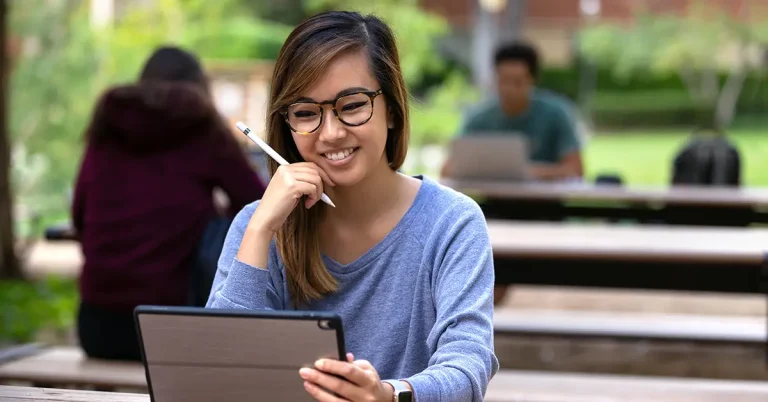 A high school student studying with a digital tablet and stylus outdoors, preparing for the SAT using an online prep guide
