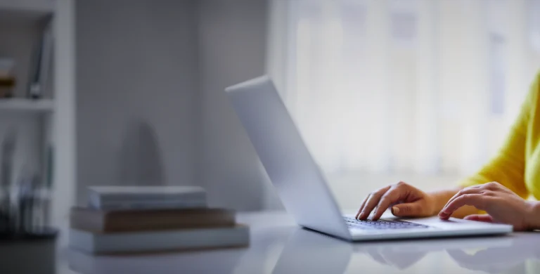 A student wearing a yellow sweater taking the SAT on her laptop.
